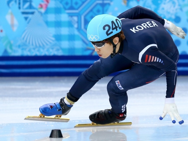 Спортсмен входит в поворот на соревнованиях по скоростному бегу на коньках на Олимпиаде в Сочи