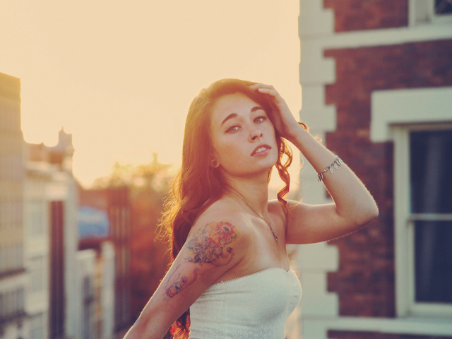 Девушка на закате с татуировкой на плече