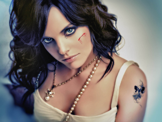 Шрам на щеке и татуировка на плече у девушки