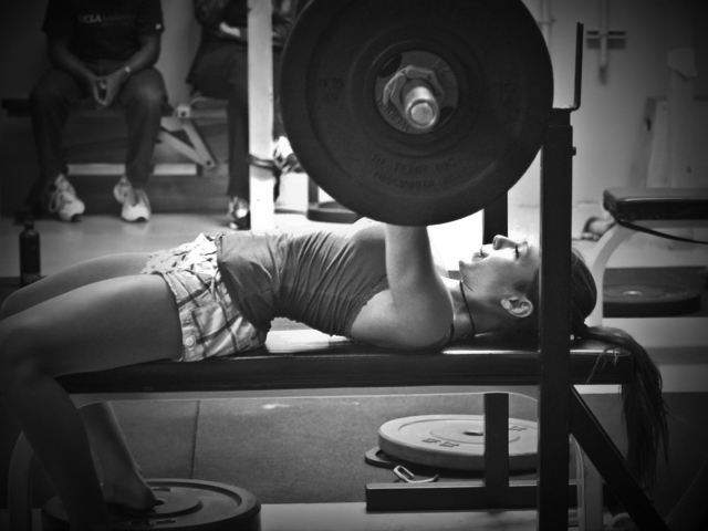 Спортивная девушка поднимаeт тяжести