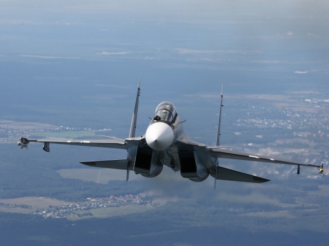 Самолет СУ-27 летит над городом