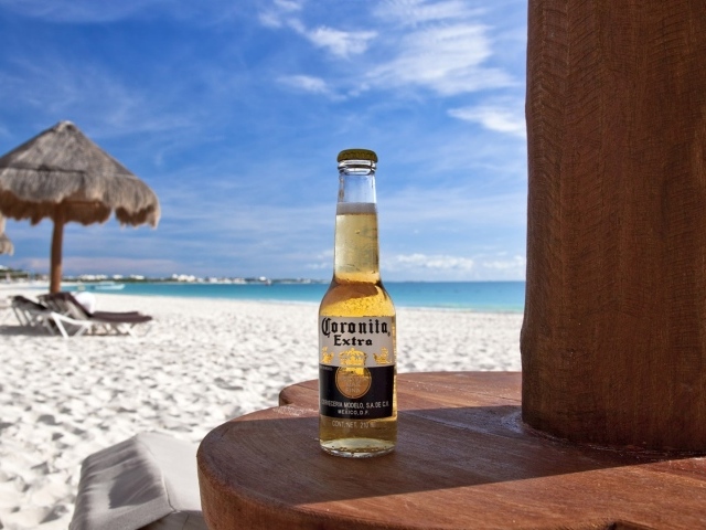Бутылка холодного пива на столе на пляже