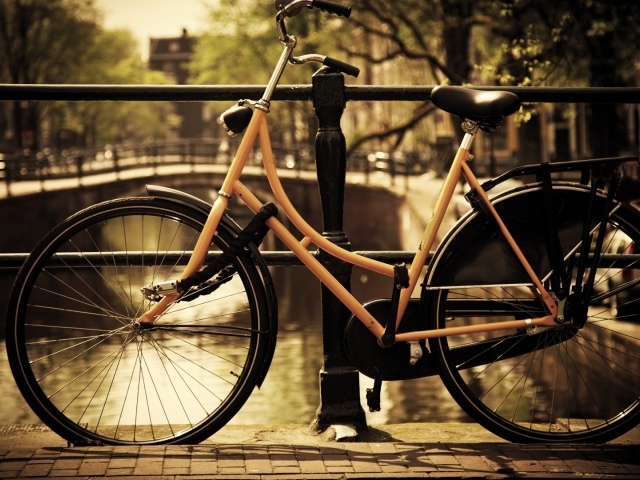 Оранжевый велосипед прислонен к перилам