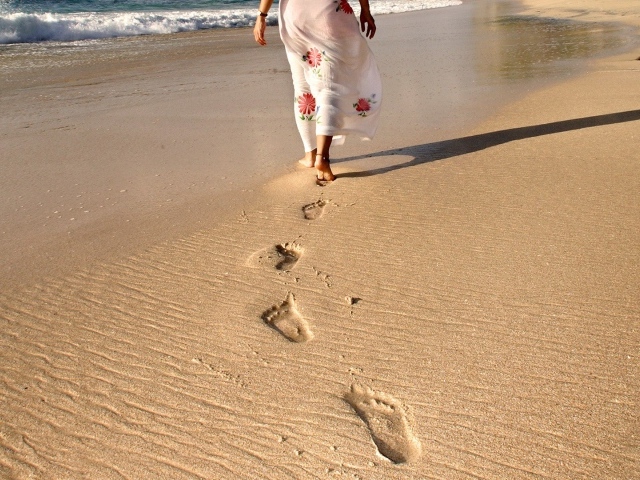Следы босых ног на песке пляжа