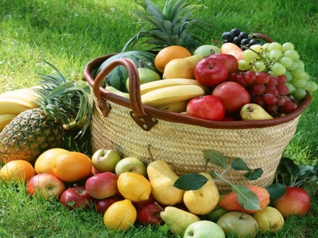 Корзина разнообразных фруктов на зеленом газоне
