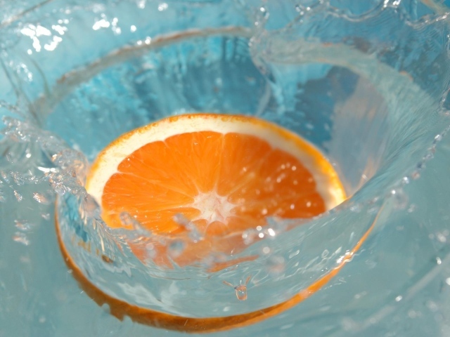 Кружок апельсина падает в воду