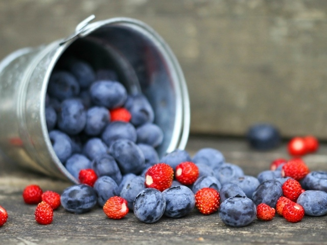 Плоды клубники и сливы в ведре