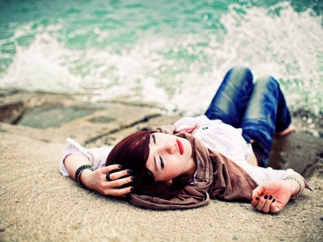 Босая девушка в джинсах лежит на набережной