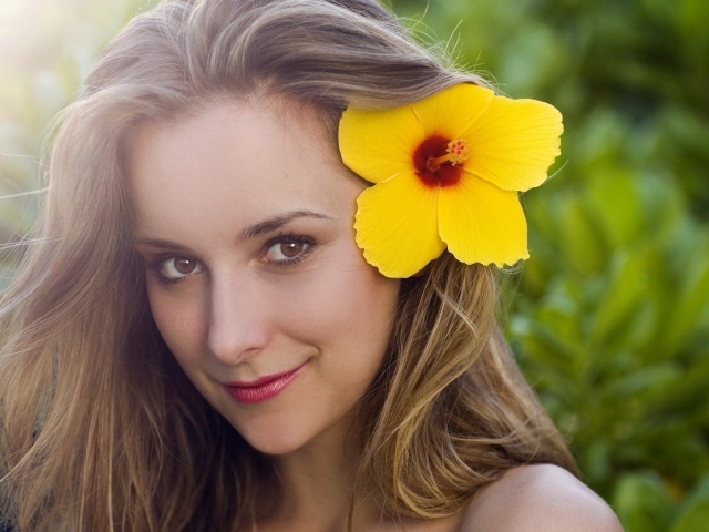 Большой желтый цветок в волосах у девушки