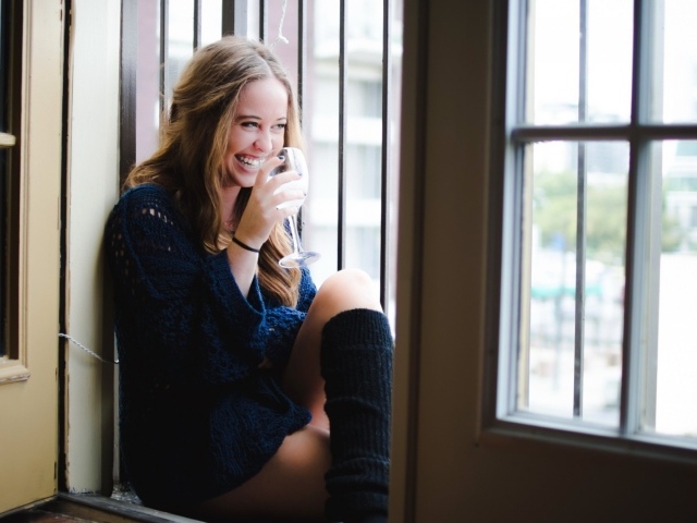 Блондинка пьет вино и смеется