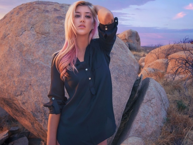 Блондинка стоит у большого валуна