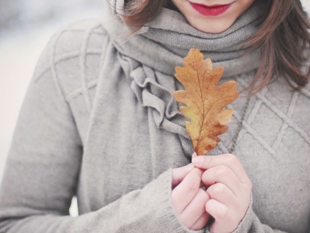 Девушка держит в руках желтый лист