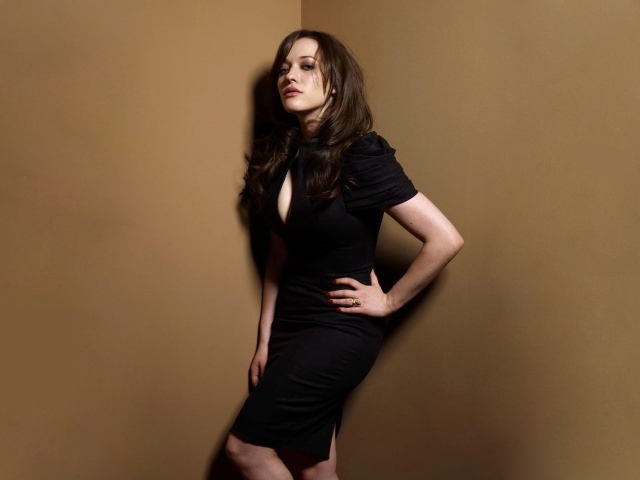 Девушка в черном платье стоит в углу