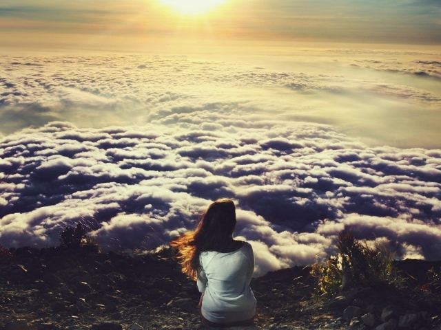 Девушка сидит и смотрит на облака