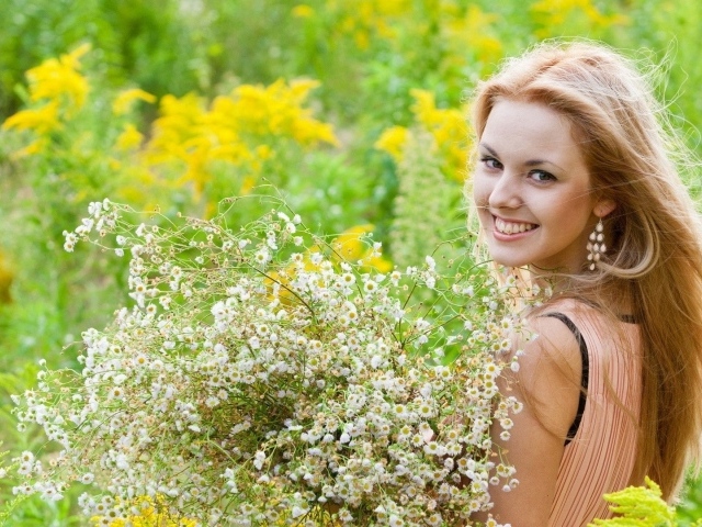 Девушка улыбается, держа в руках букет ромашек