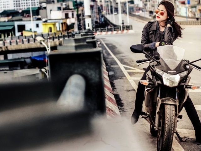 Девушка в темных очках сидит на мотоцикле