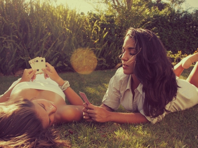 Девушки играют в карты на газоне