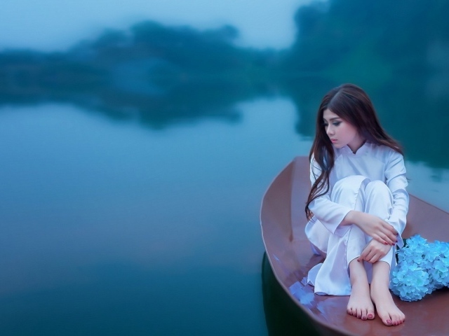 Японская девушка сидит в лодке на озере