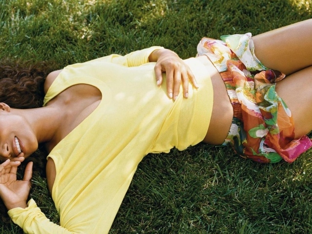 Мулатка в желтой футболке лежит на траве