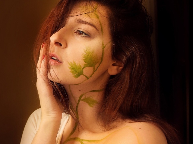 Рисунок зеленых листьев на лице и шее девушки