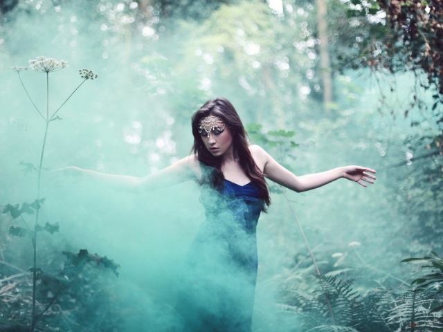 Девушка идет среди дыма по лесу