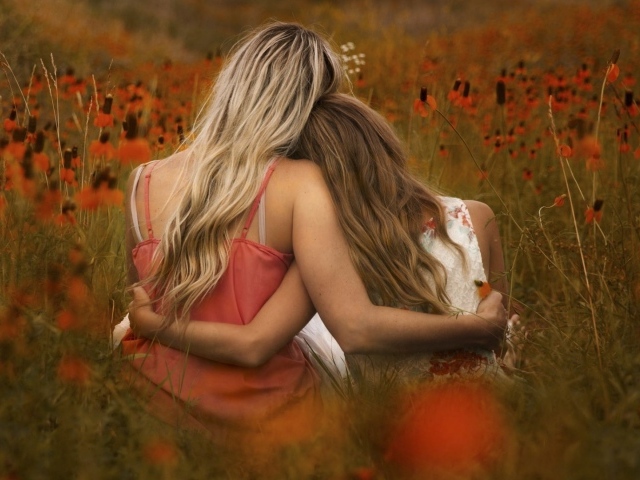 Две девушки сидят обнявшись в поле