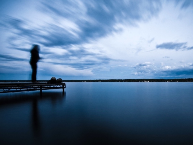 Силуэт человека на пристани у озера