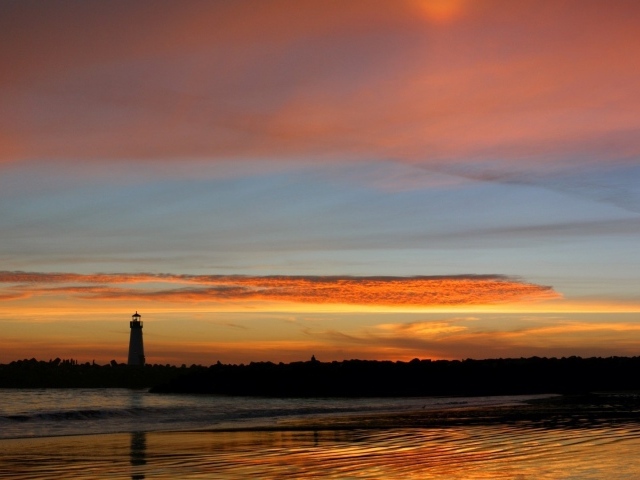 Силуэт маяка на фоне оранжевых облаков