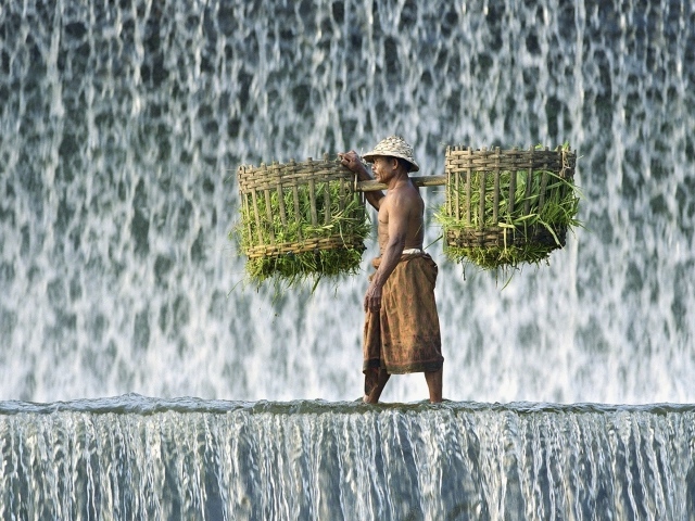 Крестьянин с корзинами идет по водопаду