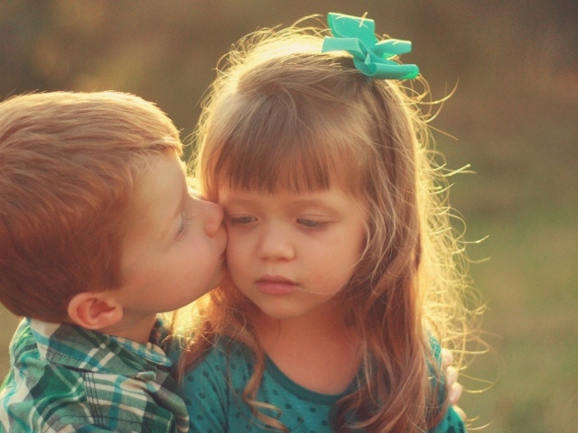 Мальчик целует сестренку в щеку