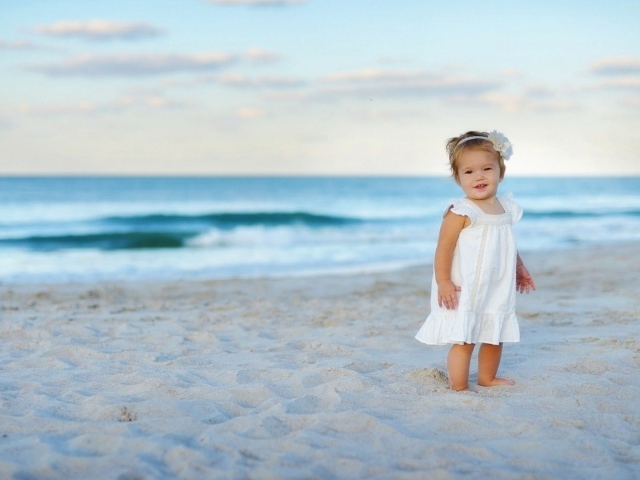 Девочка в белом платье на песке пляжа