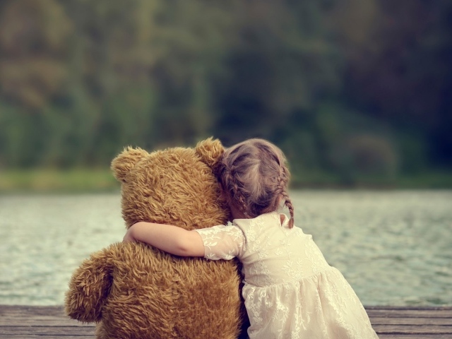 Девочка сидит в обнимку с плюшевым медведем