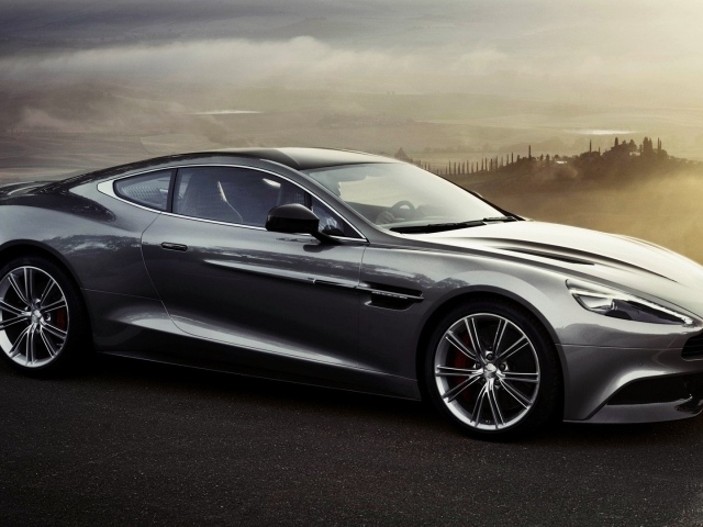 Темно серый Aston Martin на фоне туманной долины