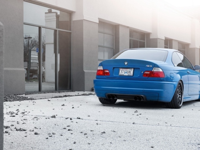 Голубой BMW на бетонной площадке у дома