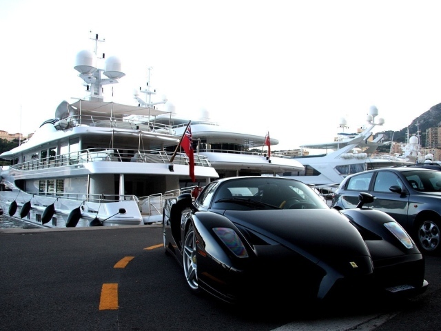Черный Ferrari на фоне белой яхты