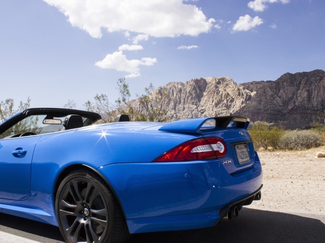 Голубой кабриолет Jaguar на фоне гор