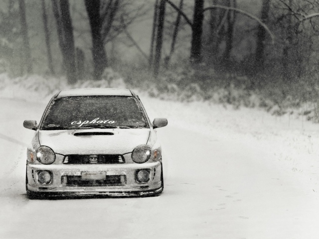 Покрытый снегом Subaru Impreza на зимней дороге