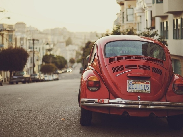 Красный Volkswagen Beetle припаркован на краю улицы