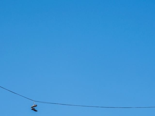 Кеды висят на проводе на фоне голубого неба