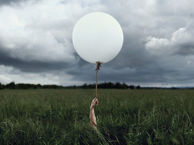 Рука с шаром среди поля