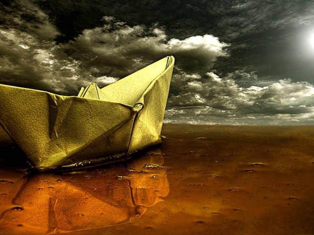 Корабль из бумаги на мокром песке