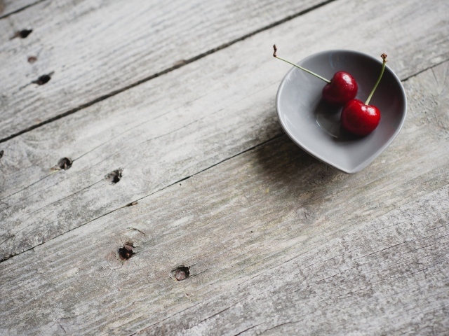Две красных вишни в керамической чашке