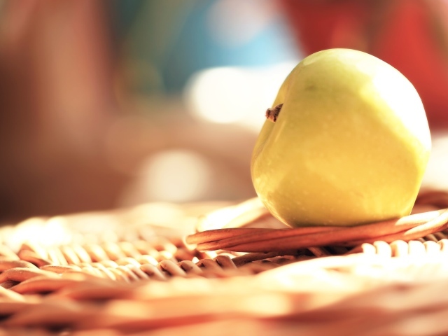 Белое яблоко на плетеной подставке