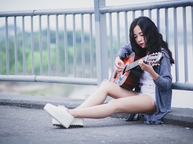 Азиатка брюнетка с гитарой на мосту