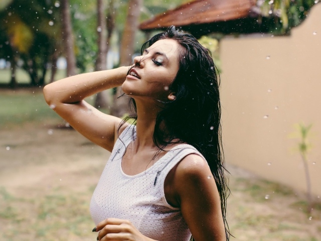 Брюнетка подставляет лицо под капли дождя