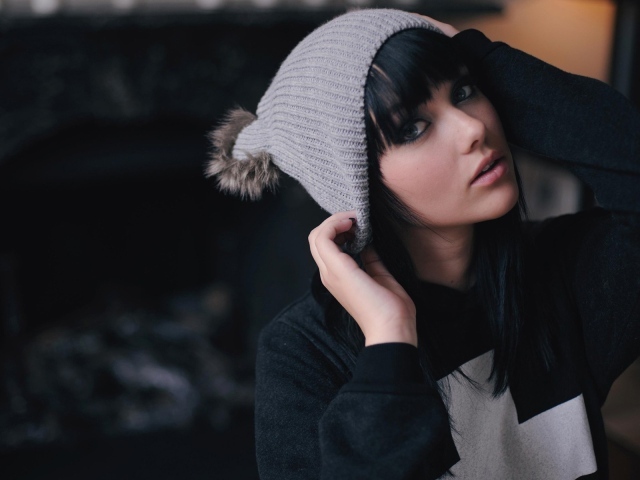 Брюнетка одевает вязаную шапочку