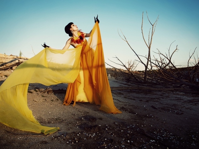 Девушка в оранжевом позирует в пустыне