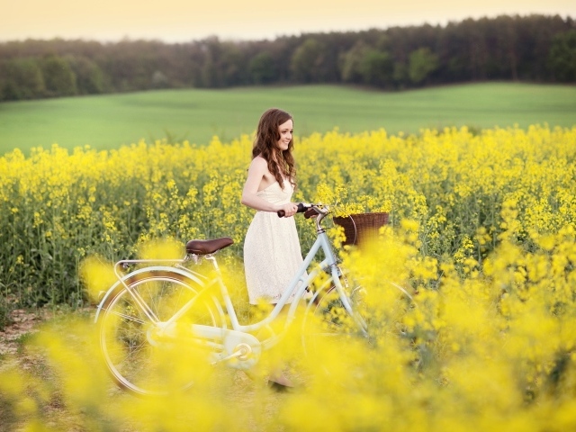 Девушка на велосипеде среди желтых цветов