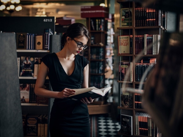 Девушка читает среди книжных полок