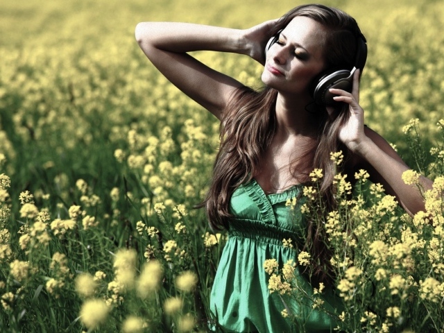 Девушка стоит среди цветов в наушниках